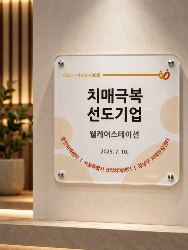 웰케어스테이션 치매극복 선도기업 지정 현판 — 지정번호 제25-1-1-60-480호, 2025. 7. 10. 중앙치매센터 · 서울특별시 광역치매센터 · 강남구 치매안심센터 지정